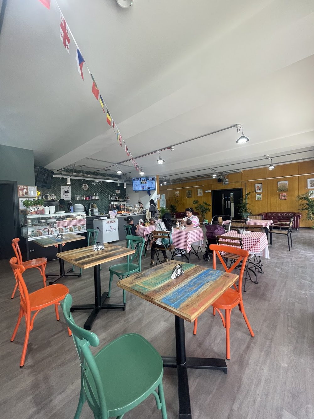 The seating room with orange and green chairs, painted table tops and bunting overhead