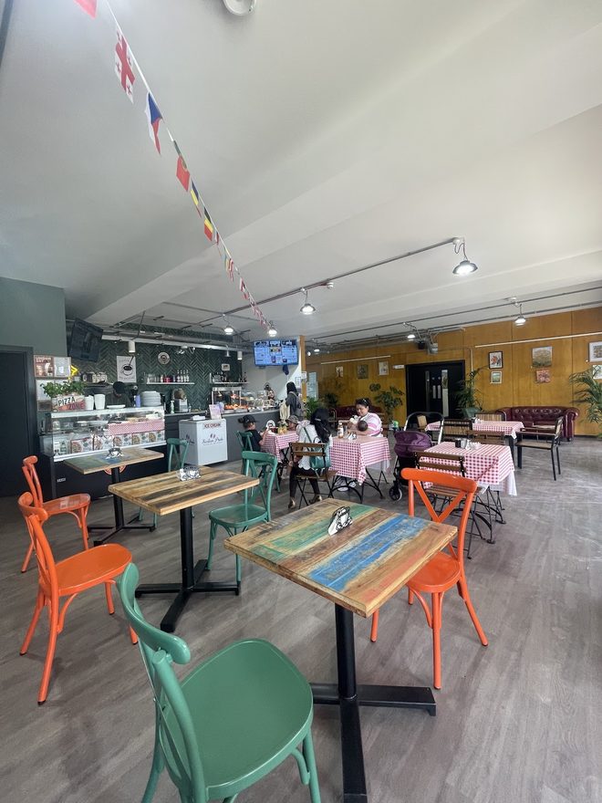 Orange and green chairs, painted tables and bunting overhead