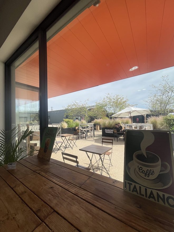The decked outdoor terrace under an orange soffit, looking out to tables and a parasol
